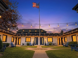 A hotel with a flagpole, string lights, and outdoor seating. - Franklin Park Studio Kitchen + Workspace (Columbus)