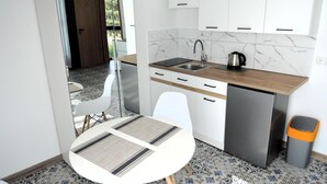 Een kleine keuken met witte kastjes, een roestvrijstalen koelkast en een koffiezetapparaat.