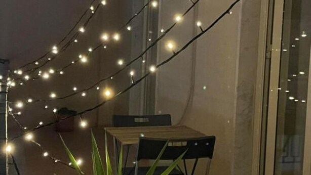 Un coin repas avec une table et des chaises, décoré de guirlandes lumineuses.
