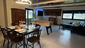 A spacious living area with a wooden ceiling, a dining table set for four, and a sofa in the background. - Orchard Villa, Lakes Bled and Bohinj (Bled)