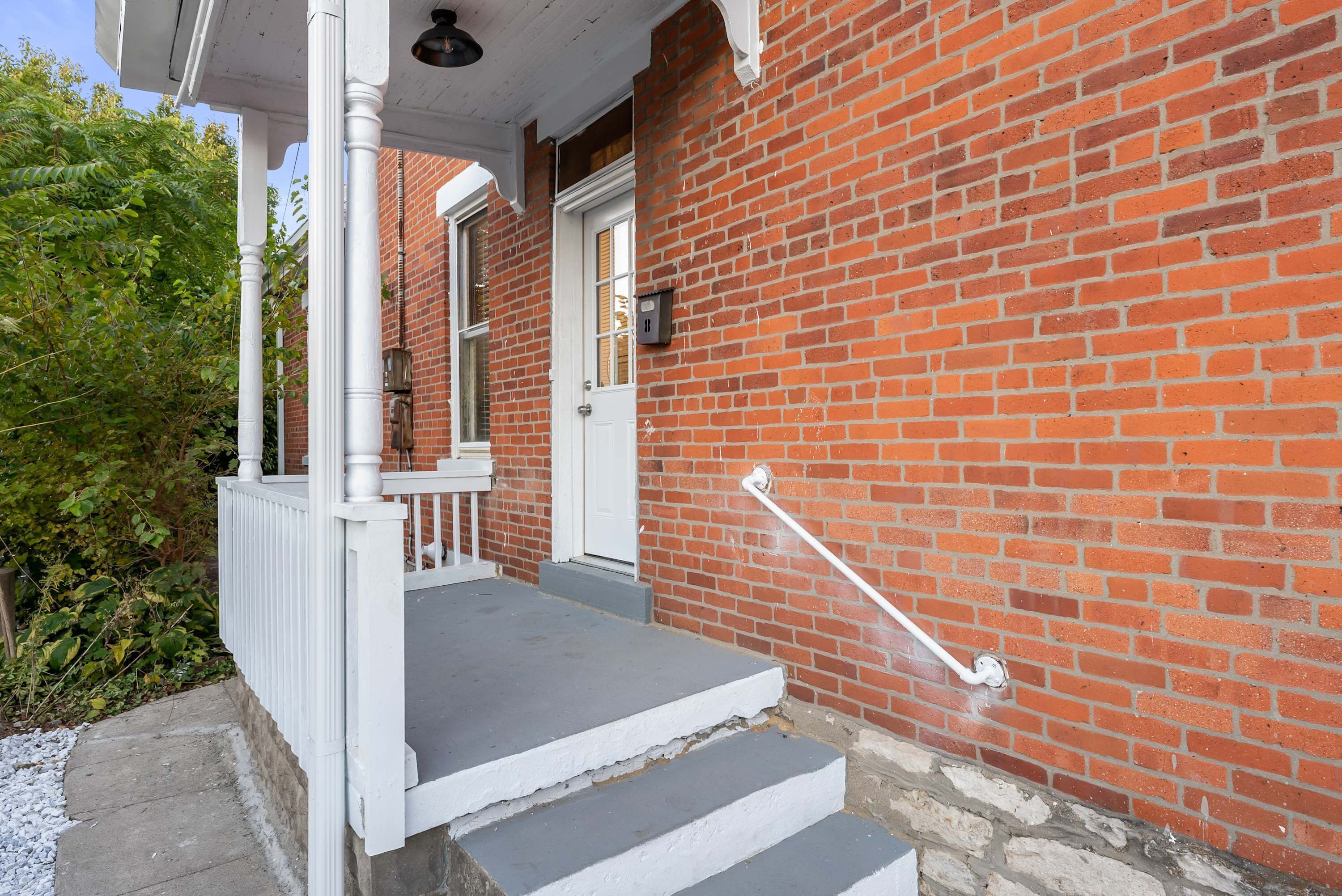 A brick building with a white door and steps leading to a porch.