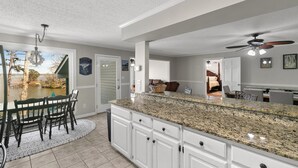 A kitchen with a granite countertop, white cabinets, and a dining area with a table and chairs. - BIG WATER views in Abbeville: 3BR, Master Ste, Hot Tub, Ice Machine, Beach Area (Abbeville)