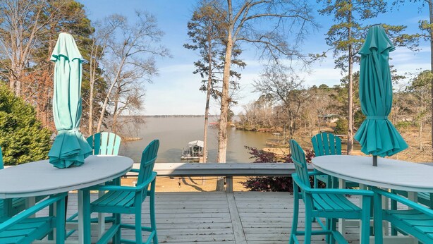 A wooden deck with turquoise chairs and umbrellas overlooking a lake. - BIG WATER views in Abbeville: 3BR, Master Ste, Hot Tub, Ice Machine, Beach Area (Abbeville)