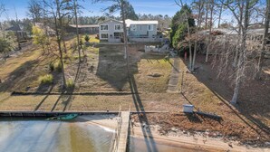 A residential area with a dock extending into a body of water, surrounded by trees and houses. - BIG WATER views in Abbeville: 3BR, Master Ste, Hot Tub, Ice Machine, Beach Area (Abbeville)