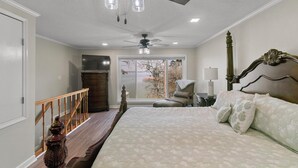 A bedroom with a large bed, a ceiling fan, a view of a lake through a window, and a wooden staircase. - BIG WATER views in Abbeville: 3BR, Master Ste, Hot Tub, Ice Machine, Beach Area (Abbeville)