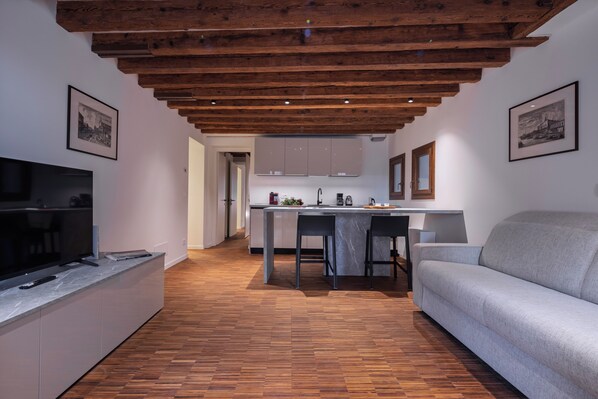 A modern living room with a sofa, a TV, and a wooden ceiling.