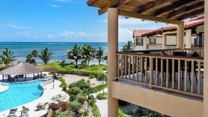 A resort with a pool, lounge chairs, and a view of the ocean. - Oceanview 2BR Condo- Pools, Beach, Spacious Balcony- Residences at Barrier Reef (San Pedro Town)