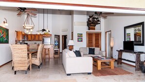 A spacious living area with a dining set, a sofa, and a coffee table. - Oceanview 2BR Condo- Pools, Beach, Spacious Balcony- Residences at Barrier Reef (San Pedro Town)