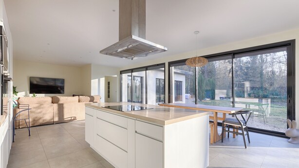 A modern kitchen with a central island, large windows, and a view of the outdoors. - Villa Carotte à 10 Minutes de Disneyland Paris (Chalifert)