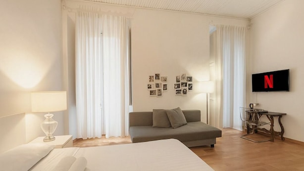 Een hotelkamer met een bed, een slaapbank, een televisie en een tafel.