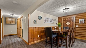 A dining area with a wooden table and chairs, a wall clock, and a sign reading "ICE BAIT TACKLE". - Lake Cumberland Cedar Hideaway (Burnside)