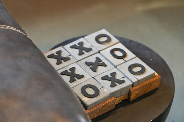 Primer plano de un juego de tres en raya con bloques de madera sobre una superficie oscura.
