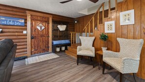 A cozy cabin interior with a wooden interior, a ceiling fan, a bench, two armchairs, and a sign that reads "on lake time". - Lake Cumberland Cedar Hideaway (Burnside)