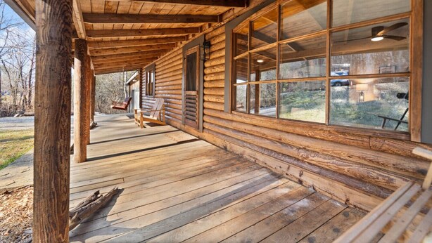 A wooden cabin with a covered porch, large windows, and a view of the surrounding landscape. - Lake Cumberland Cedar Hideaway (Burnside)