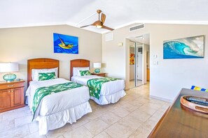 A hotel room with two beds, a wooden headboard, a ceiling fan, and artwork on the walls.