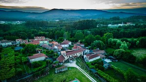 An aerial view of a village with houses surrounded by greenery and mountains in the background. - O lagar de Jesús (Padron)