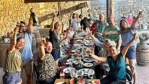A group of people celebrating at an outdoor dining area with stone walls and wooden beams. - O lagar de Jesús (Padron)