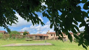 A stone building with a red-tiled roof, surrounded by a well-maintained lawn and a paved area. - O lagar de Jesús (Padron)