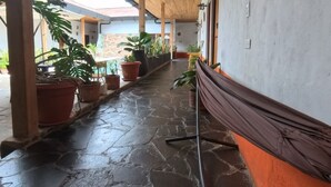 A covered corridor with wooden ceiling, stone flooring, potted plants, and a bench. - Hotel Alcazar Real (Útica)
