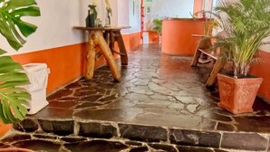 A hallway with a stone floor, wooden ceiling, and potted plants. - Hotel Alcazar Real (Útica)