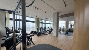 A spacious gym with various exercise equipment, large windows, and a view of the city. - Great New Modern Department Expo GDL (Guadalajara)