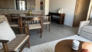 A modern living room with a round wooden coffee table, a sofa, and a dining area with a round table and chairs. - Luxurious and Spacious Apartment in Centro Zapopan (Zapopan)