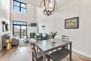 A spacious living area with a fireplace, a dining table, and a large window.