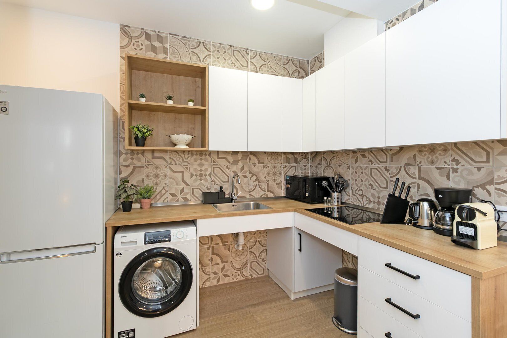 Una cocina compacta equipada con lavadora, microondas y cafetera.