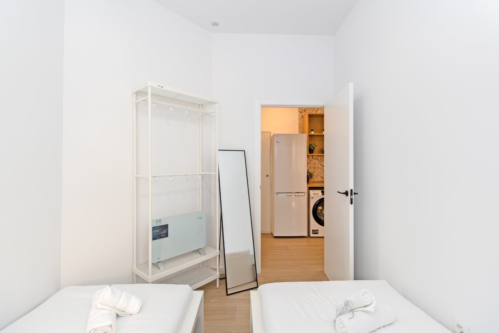 A small, modern room with two beds, a wardrobe, a washing machine, and a whiteboard.