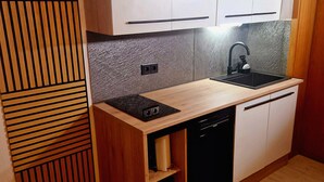 A compact kitchen with white cabinets, a black sink, and a dishwasher. - Central, cozy apartment, 50 mts away from the old town in Höxter. (Höxter)