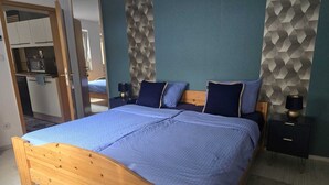 A bedroom with a wooden bed, a nightstand, a lamp, and a geometric-patterned wall. - Central, cozy apartment, 50 mts away from the old town in Höxter. (Höxter)