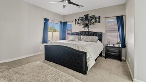 A bedroom with a large bed, a ceiling fan, and a nightstand with a lamp. - Amazing Gilbert Retreat (Gilbert)