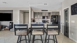 A modern kitchen with a central island, bar stools, and a dining table. - Amazing Gilbert Retreat (Gilbert)