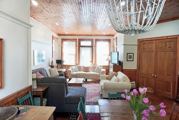 Un ampio soggiorno con pavimento in legno, un lampadario e un'ampia porta di legno.