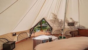 A tent with a bed, a chair, and a small table.