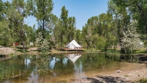 A cabin on stilts over a pond, surrounded by trees.