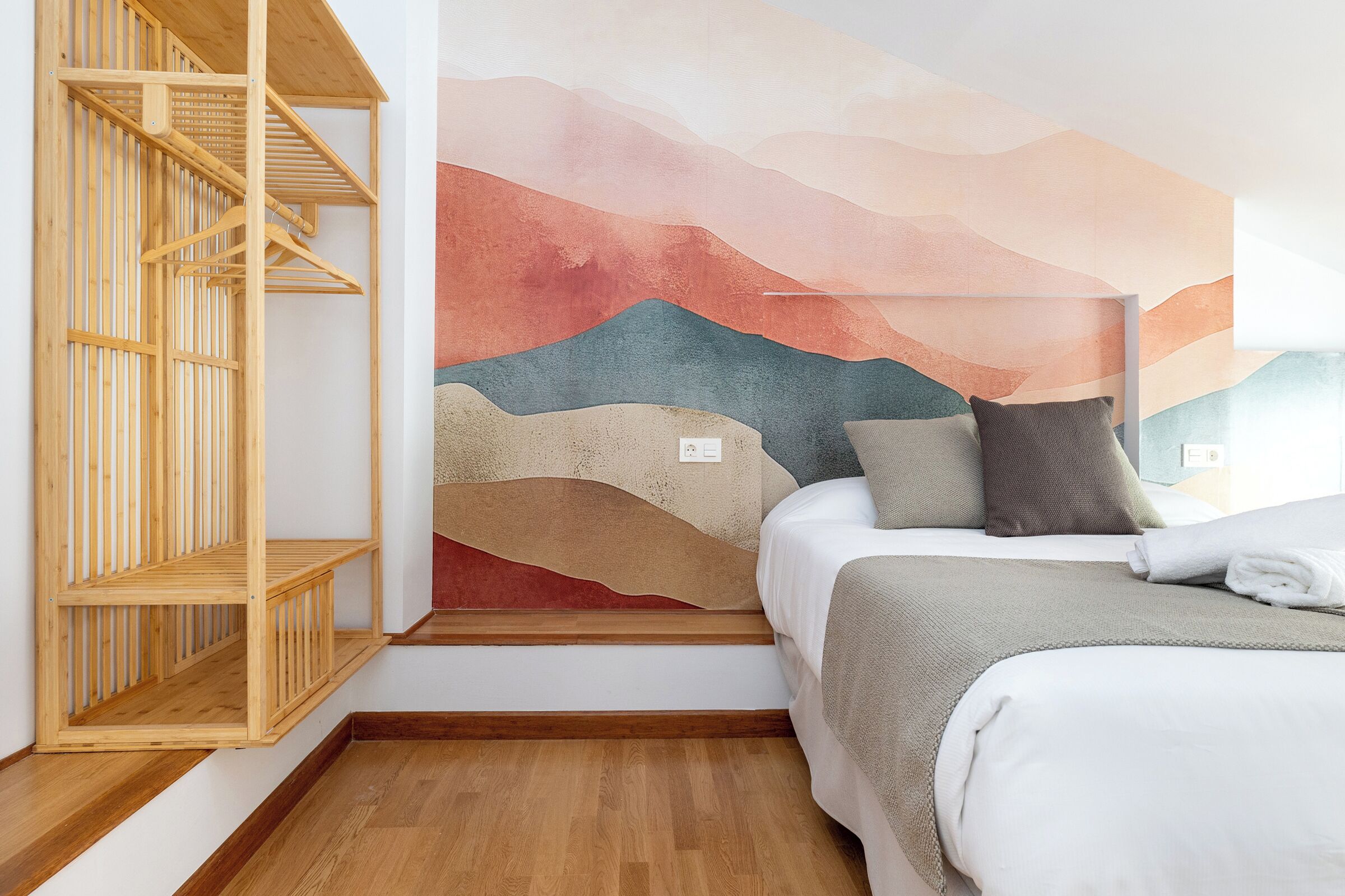 Un dormitorio con una cama, una estantería de madera y un mural en la pared.