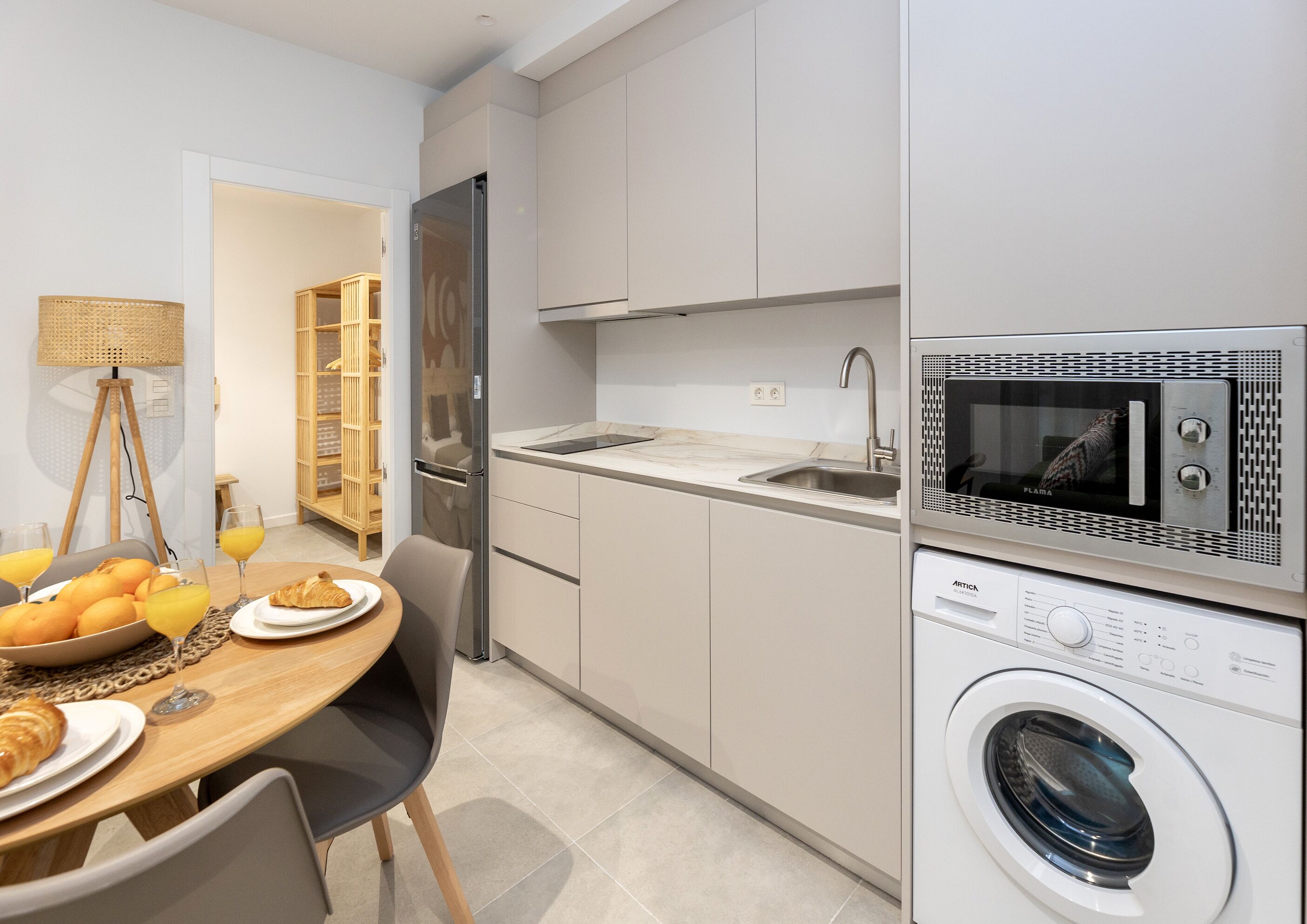 A compact kitchen with a built-in microwave, a washing machine, and a sink.