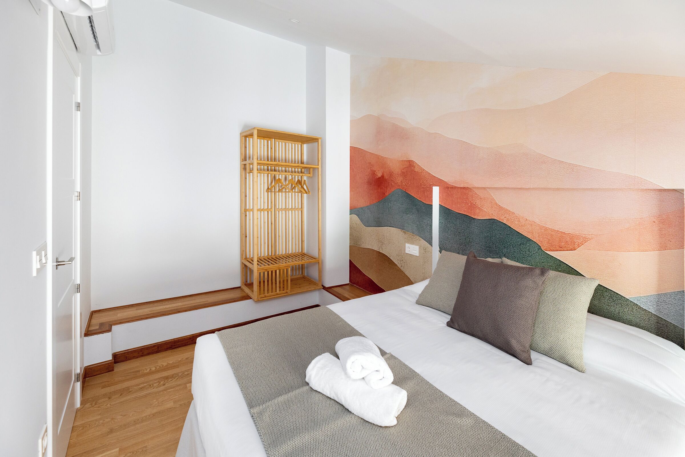 Una habitación de hotel con una cama, un armario de madera y un mural en la pared.