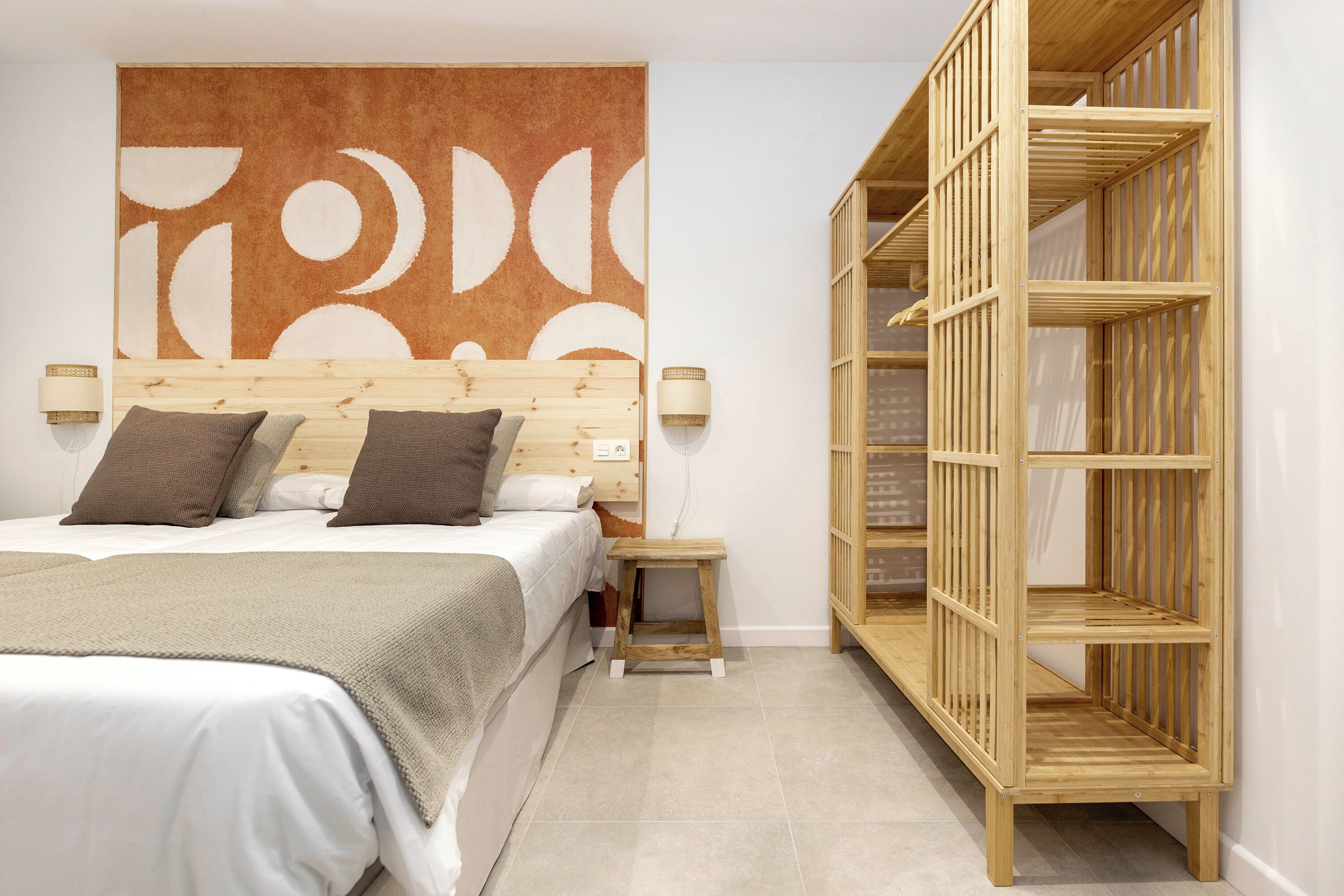 Une chambre à coucher comprenant un lit, des tables de chevet, une armoire en bois et une grande œuvre d’art abstraite accrochée au mur.