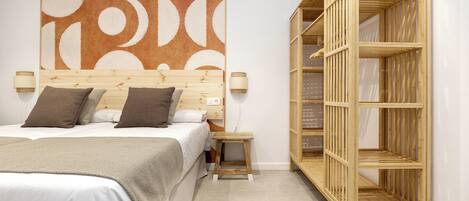 Un dormitorio con cama, mesitas de noche, un armario de madera y una gran obra de arte abstracta en la pared.