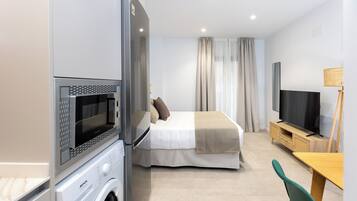 Ein modernes Hotelzimmer mit Bett, Fernseher, Waschmaschine und Essecke.