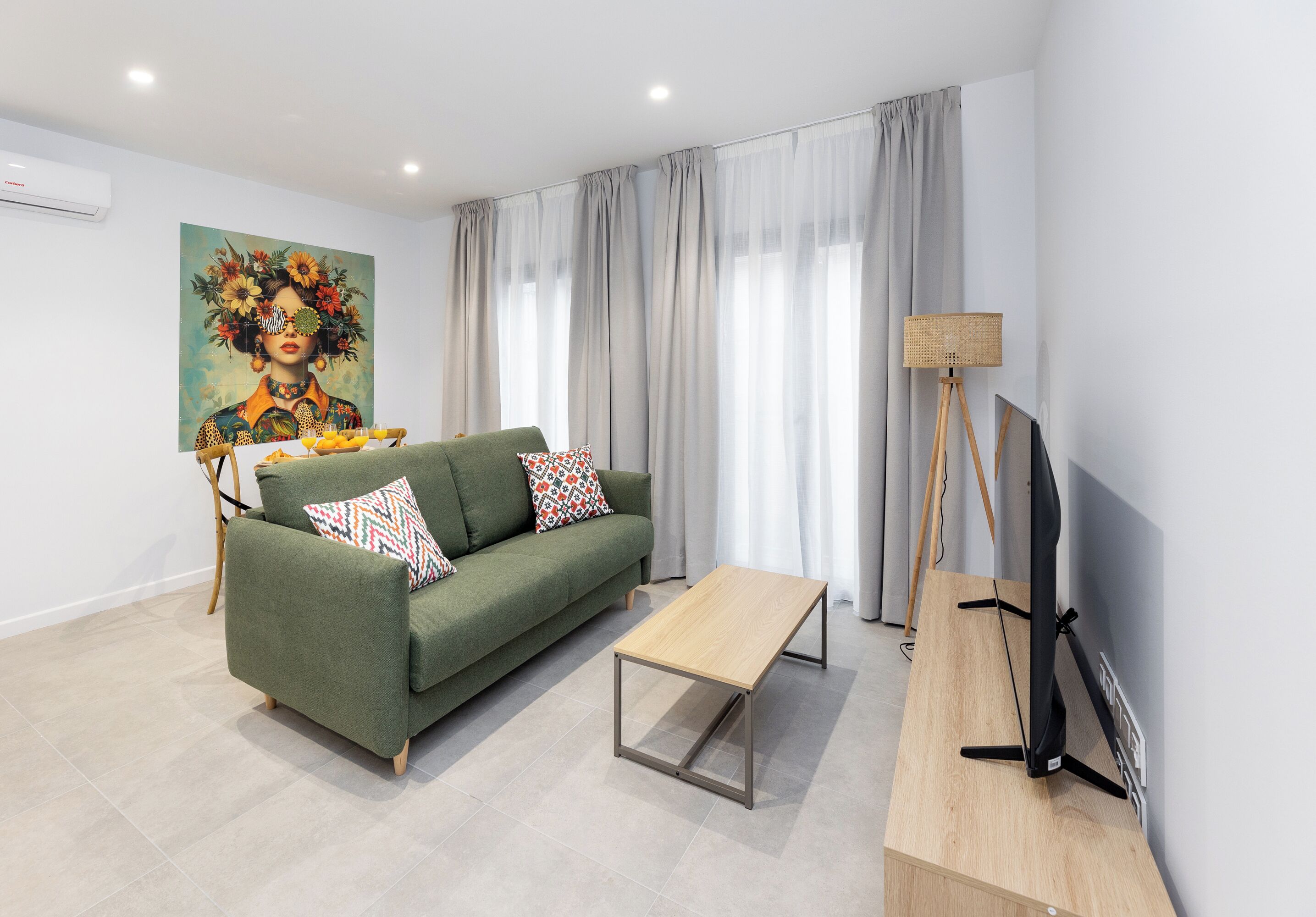 A modern living room with a green sofa, a wooden coffee table, and a painting on the wall.