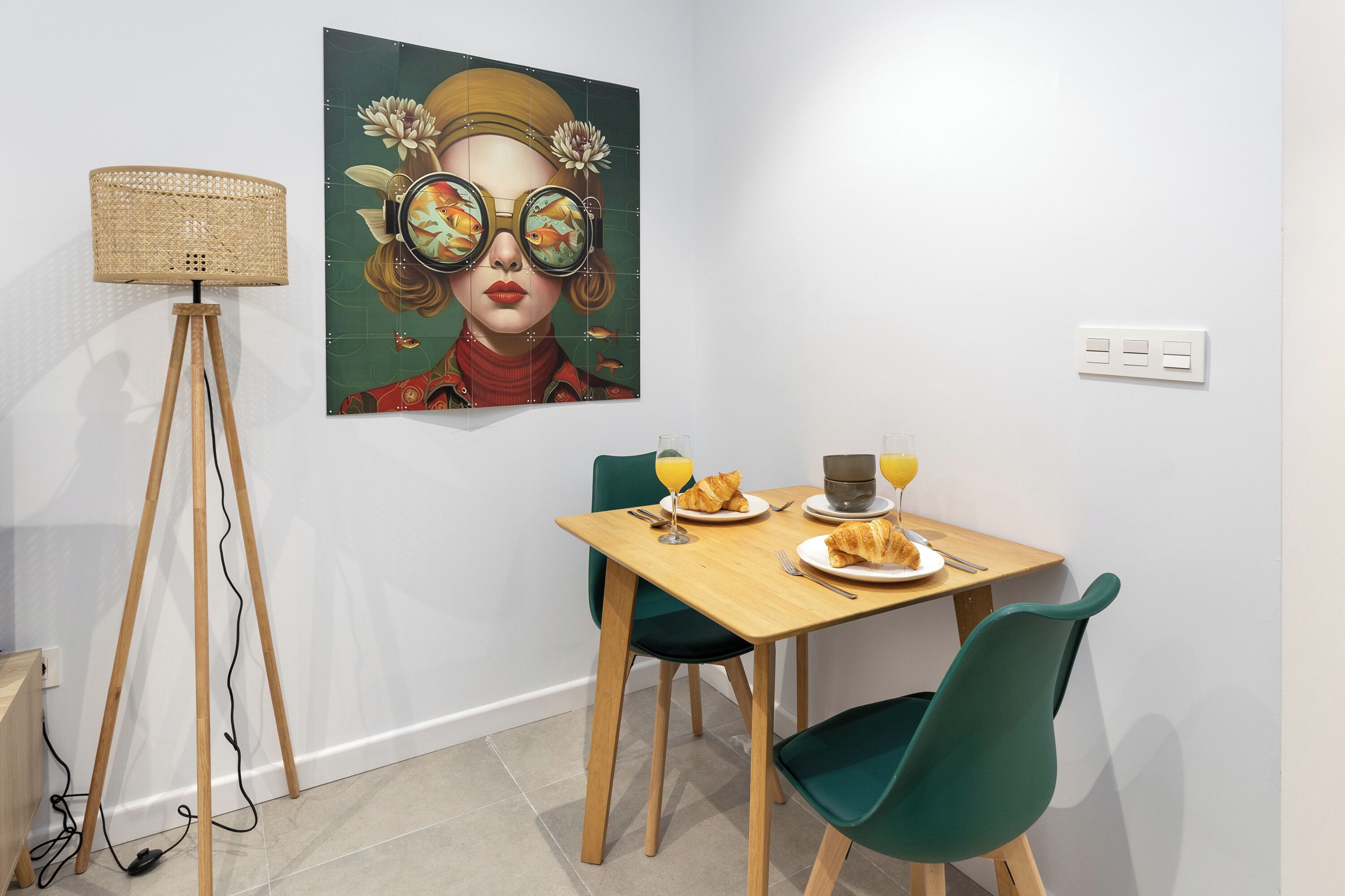 Uma sala de jantar com uma mesa de madeira, cadeiras verdes e um quadro na parede.