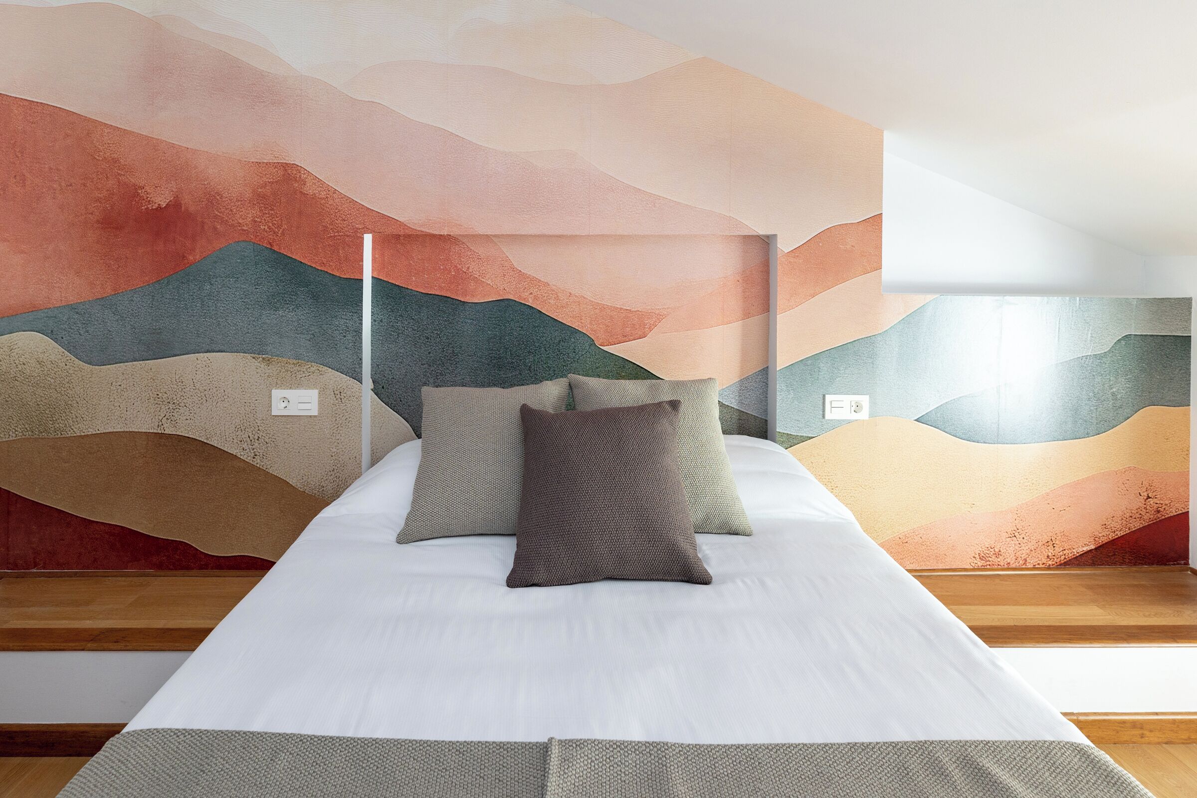 Una cama bien hecha con almohadas y un mural texturizado en la pared.