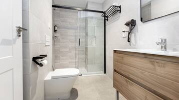 Un baño moderno con inodoro, ducha y tocador.