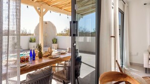 A dining area with a table set for two, a glass partition, and a view of the outdoors.