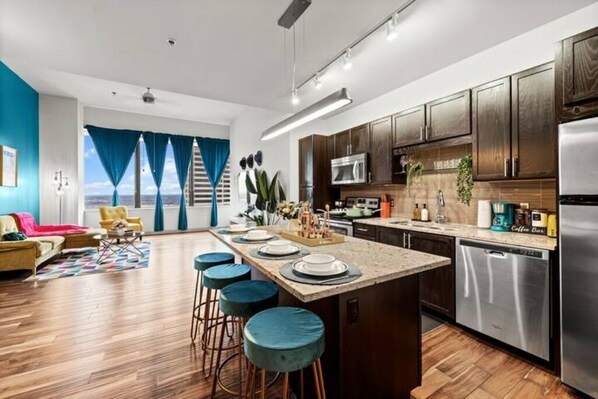 A modern kitchen with a central island, stainless steel appliances, and a large window with curtains.
