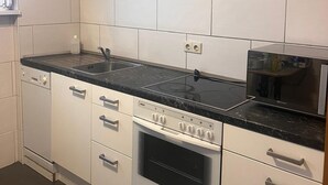 A modern kitchen with white cabinets, a black countertop, a Bosch oven, and a microwave. - NR 3 Apartment on the upper floor 3 ZKB for companies/families (Vellmar)