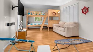 Ein kleines Zimmer mit Etagenbett, einer Schlafcouch, einem kleinen Tisch und einem Fenster.